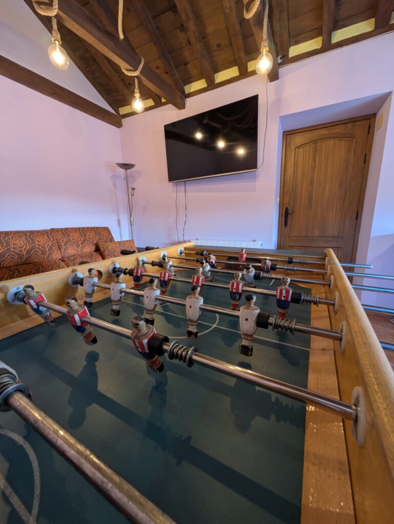 Futbolín en habitación con televisor y luces colgantes.